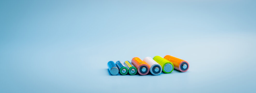 Rechargeable battery on blue background. Selective focus negative terminals of rechargeable lithium-ion batteries. AA and AAA size of old Li-ion battery. Battery recycling concept. Green power energy.