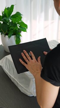 Person holding small parcel with compact QR code label compared to larger package at home. Different sizes of tracking codes for shipping and logistics concept.