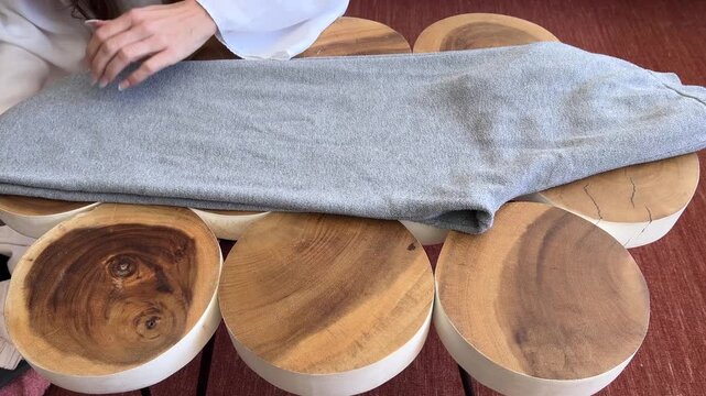 Manos de mujer doblando un pantal&oacute;n gris sobre la mesa
