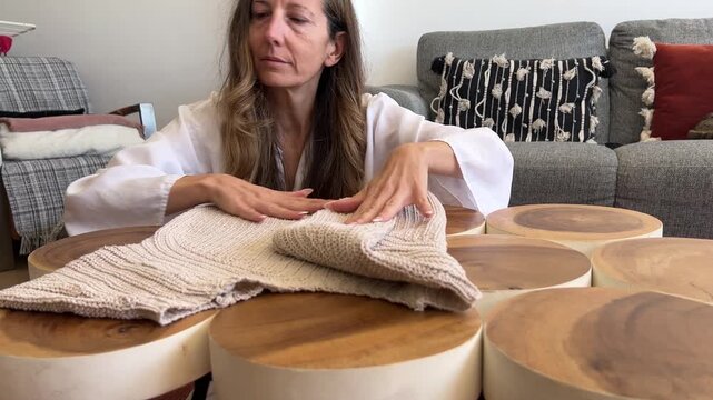 Mujer doblando un jersey beige perfectamente