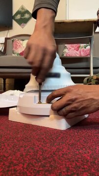 An electrician is fixing a brand new ceiling fan. 