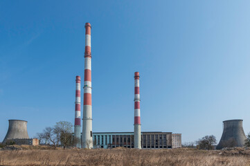 Elektrociepłownia EC2 w Łodzi w trakcie rozbiórki. Industrialna architektura z czerwono-białymi kominami i chłodniami kominowymi na tle błękitnego nieba. © smoku7979