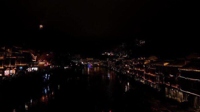Serene night scenery. Calm waterside hamlet illuminated softly by moonlight and tranquil surroundings