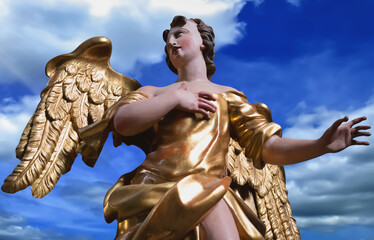 Golden angel against blue sky, symbol of hope, protection and divine inspiration