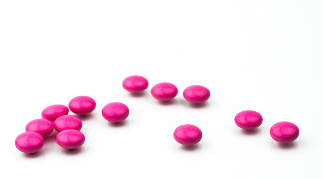 Pile of pink round sugar coated tablets pills isolated on white background with copy space. Colorful pills for treatment anti anxiety, antidepressant and migraine headache prophylaxis.