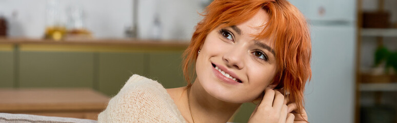 Naklejka premium Young woman with radiant red hair smiles while relaxing in her cozy home environment