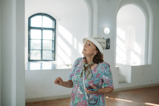 An elderly woman conducts a guided tour of an ancient castle. The pensioner examines historical artifacts at the exhibition