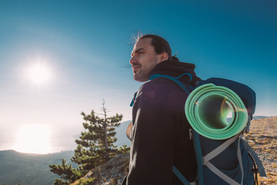 Male tourist with a backpack on the top of the mountain at sunrise