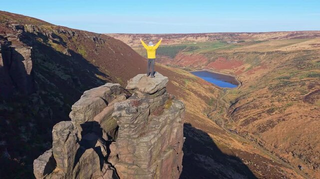 Drone POV of Man standing on the highly exposed rock. The Trinnacle is a remote and highly exposed rock formation in the Peak District near the town of Oldham at around 900ft in altitude.