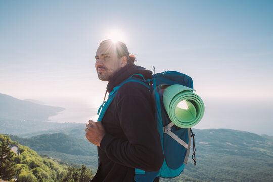 Male tourist with a backpack on the top of the mountain at sunris