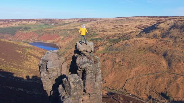 Drone POV of Man dancing on the highly exposed rock. The Trinnacle is a remote and highly exposed rock formation in the Peak District near the town of Oldham at around 900ft in altitude.