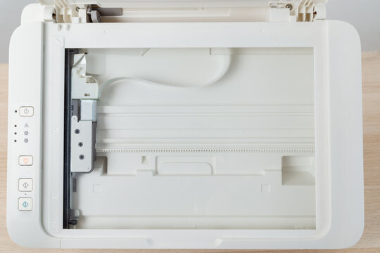 Flatbed scanner bed inside a multifunction office printer shown from above. Clean empty glass surface, control buttons and mechanism visible, document scanning, office tech and productivity.