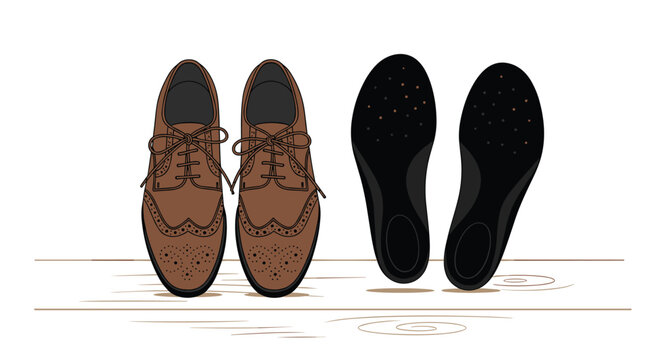 A pair of brown leather brogue shoes stands next to black shoe insoles on a light wooden surface.