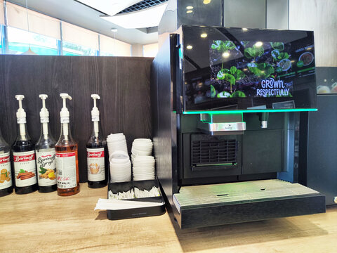 Yelabuga, Russia - June 15, 2024: Coffee machine located in a cafe with syrup dispensers and cups arranged on a wooden counter