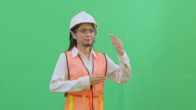 Female worker using hand signals to direct site traffic or heavy machinery. Professional coordination and safety signaling on a green screen.
