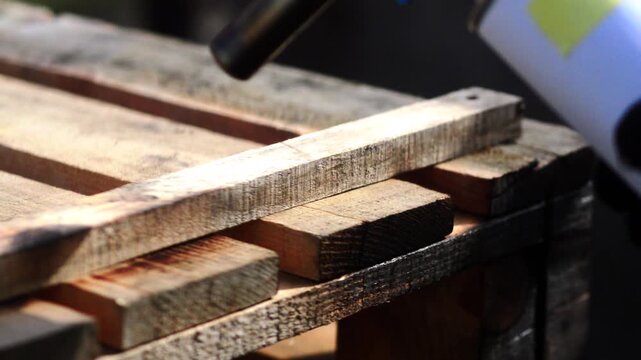 decorative burning of a wooden pallet for a street table with an old gasoline blowtorch