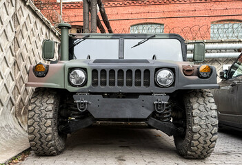 Obraz premium Military AM General HMMWV (Humvee) parked on an street, showcasing its rugged design and operational readiness in a secure military base. Khaki camouflage military Hummer front view. HMMWV.