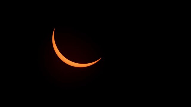 Stunning partial solar eclipse captured in Halifax, Nova Scotia on April 8, 2024. Golden crescent sun shines brightly against blue sky, rare celestial event in Canada 4K.