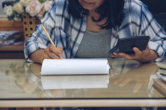 Business and Financial Planning Concept. Financial advisor Hand planning and use caculator to calculate budget, work on laptop. Professional Businesswoman writing on paper and analysis annual report a