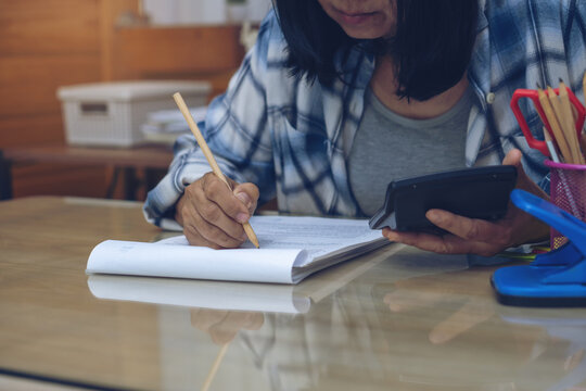 Business and Financial Planning Concept. Financial advisor Hand planning and use caculator to calculate budget, work on laptop. Professional Businesswoman writing on paper and analysis annual report a