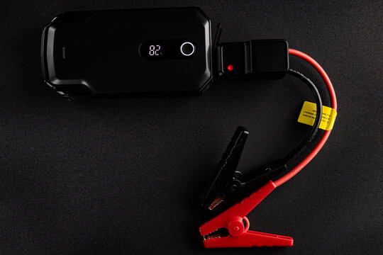 Portable Baseus jump starter and jumper cables on black background