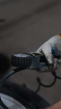 Close-up of gloved hand using air inflator with pressure gauge