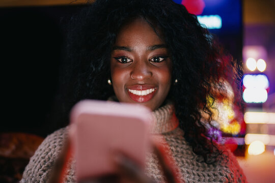 Serious woman in headphones using smartphone for remote task on street, focused female freelancer browsing application, 5G mobile network, wireless technology, digital nomad, startup culture.