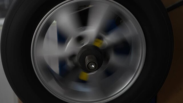 A car wheel spinning rapidly on a tire balancing machine.

