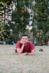 Fototapeta premium Relaxed man lying on grass with head resting on hands