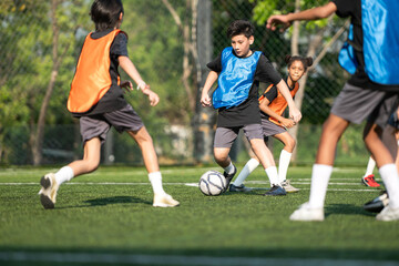 Fototapeta premium Group of international school kids playing soccer together on the field
