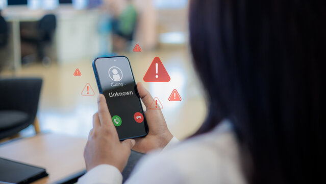 Call center scam and fraud warning.Unknown caller id with warning icon.Mobile phone phishing and cyber crime.Digital fraud protection and safety concept.Woman holding phone with phishing alert.