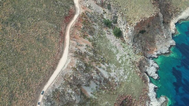 Horizontal drone video of the treacherous gravel road leading to Balos Lagoon. Cars navigate the narrow, dusty cliffside path on Gramvousa Peninsula, Crete. High quality 4k footage