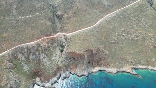 Horizontal drone video of the treacherous gravel road leading to Balos Lagoon. Cars navigate the narrow, dusty cliffside path on Gramvousa Peninsula, Crete. High quality 4k footage
