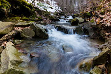 Górski strumień w wiosennym lesie pośród kamiennych głazów © kubikactive