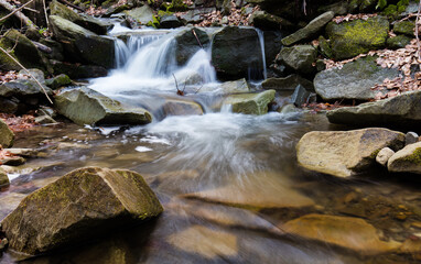 Górski strumień w wiosennym lesie pośród kamiennych głazów © kubikactive