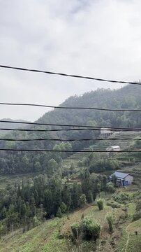 A dynamic road trip video filmed from a motorbike captures two riders navigating a narrow mountain dirt road hugging dramatic limestone cliffs along the legendary Ha Giang Loop in northern Vietnam, wi