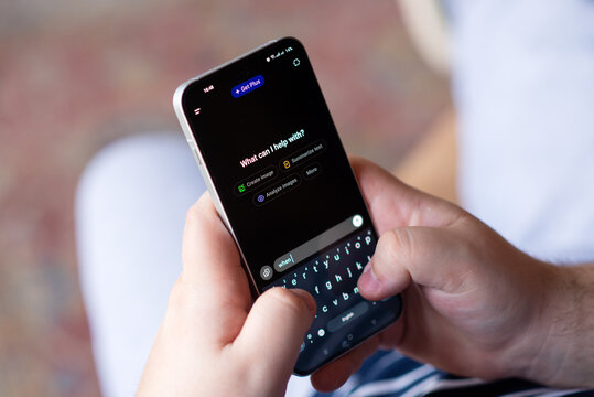 Kyiv, Ukraine. April 3, 2026. Close-up of a person's hands typing on a smartphone using an AI chatbot interface with "What can I help with?" text. 