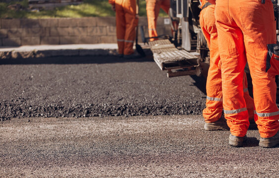 Construction worker working on a new asphalt layer on a public street.