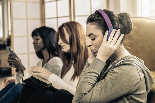 Multicultural female friends having fun individually doing different things - Concept of incommunicability between people, together but divided by different interests - Vintage editing
