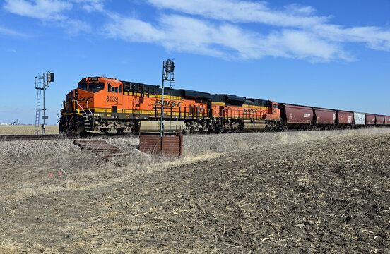 A westtbound Burlington Northern Santa Fe unit train consisting of empty grain cars resumes its journey after stopping in a passing siding in rural north cental Illinois.