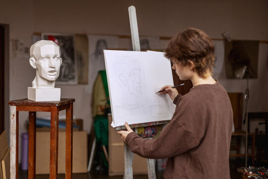 An artist draws a man's head from a plaster cast. Actual photo of an art studio. 