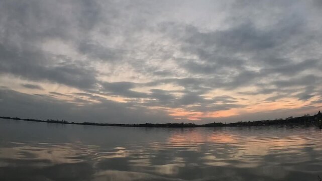 the sky and the lake, the sky in clouds, through them, illuminating them with bizarre purple colors, the sun sets very beautifully, the water reflects it and slowly ripples