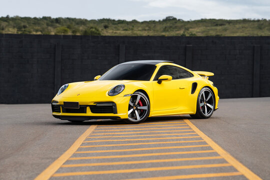 Yellow Porsche 911 Turbo front three quarters view, Luxury sports car outdoors on empty urban cenario