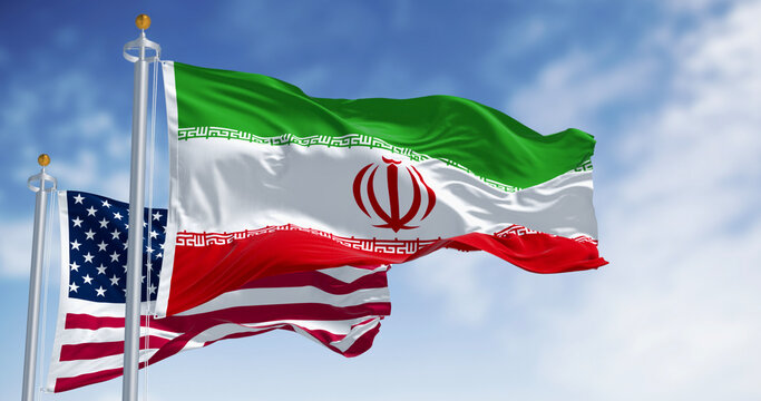 The national flags of Iran and the USA waving on a clear day