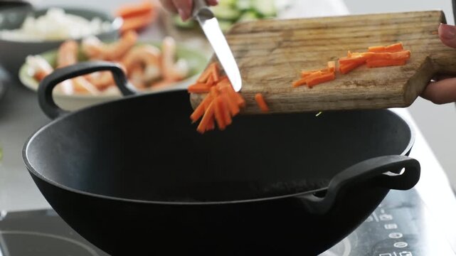 Girl Adding Chopped Carrot Into Hot Steaming Wok Pan Cooking Asian Wok Food In Kitchen