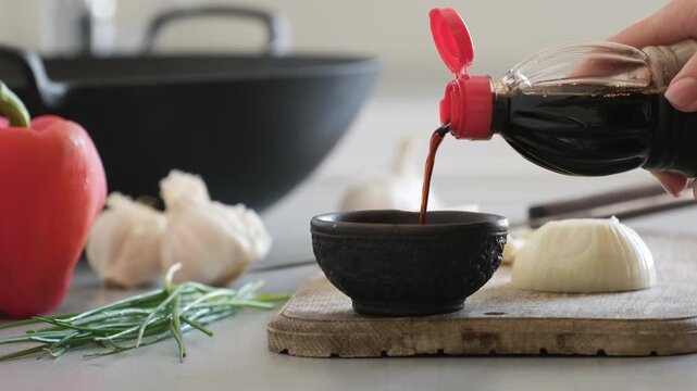Woman Pours Soy Sauce From A Bottle Into A Small Ceramic Sauce Dish For Asian Wok Food