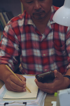 Planner or organizer writing daily appointment On Calendar book and using smartphone. Asian man hand plan timetable meeting agenda, and note schedule business in diary. Planner concept-vertical image