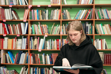 Young man reading book in a public library