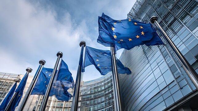 European union flags freely waving in the wind against a blue sky, standing proudly in front of a modern glass office building, symbolizing unity, democracy, and global institution