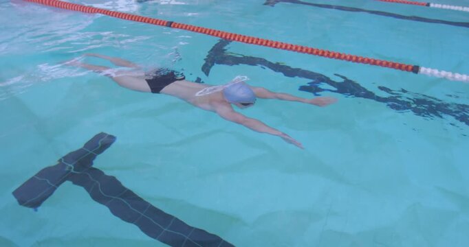 male swimmer pushing off wall gliding while flutter kicking below orange rope for stroke training